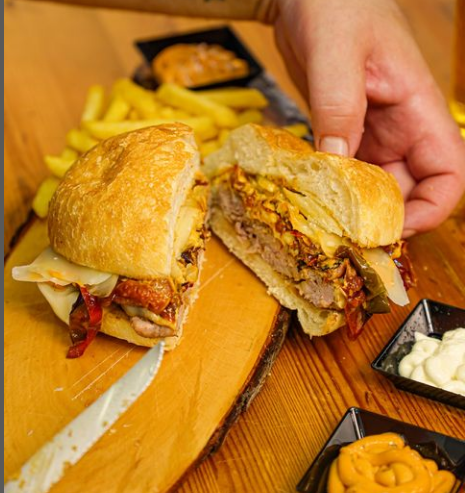Apparecchiatura del tavolo del ristorante per due con sedie color verde acqua e parete blu scuro con fiori rossi.