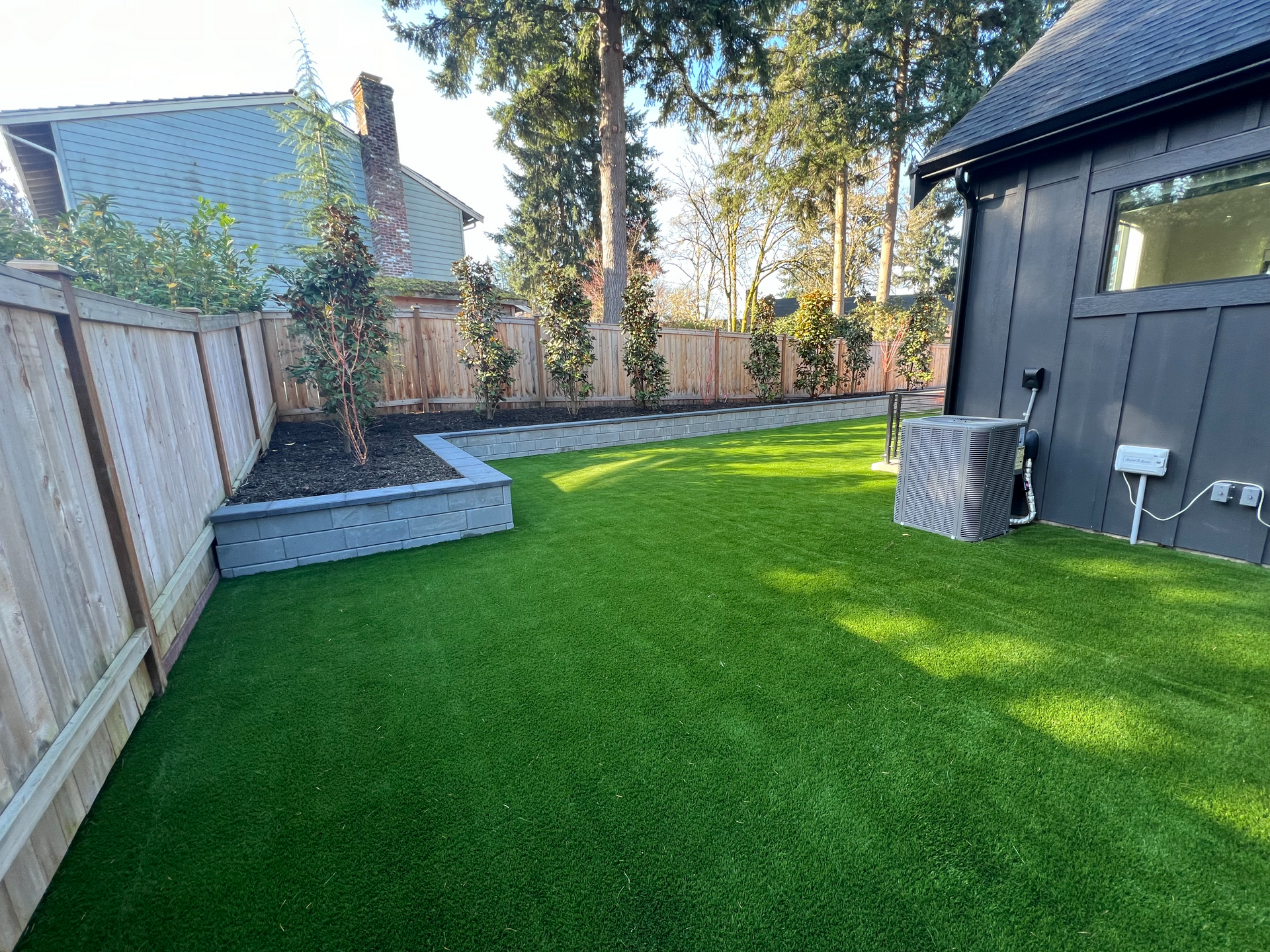 A backyard with a fence and a lush green lawn.
