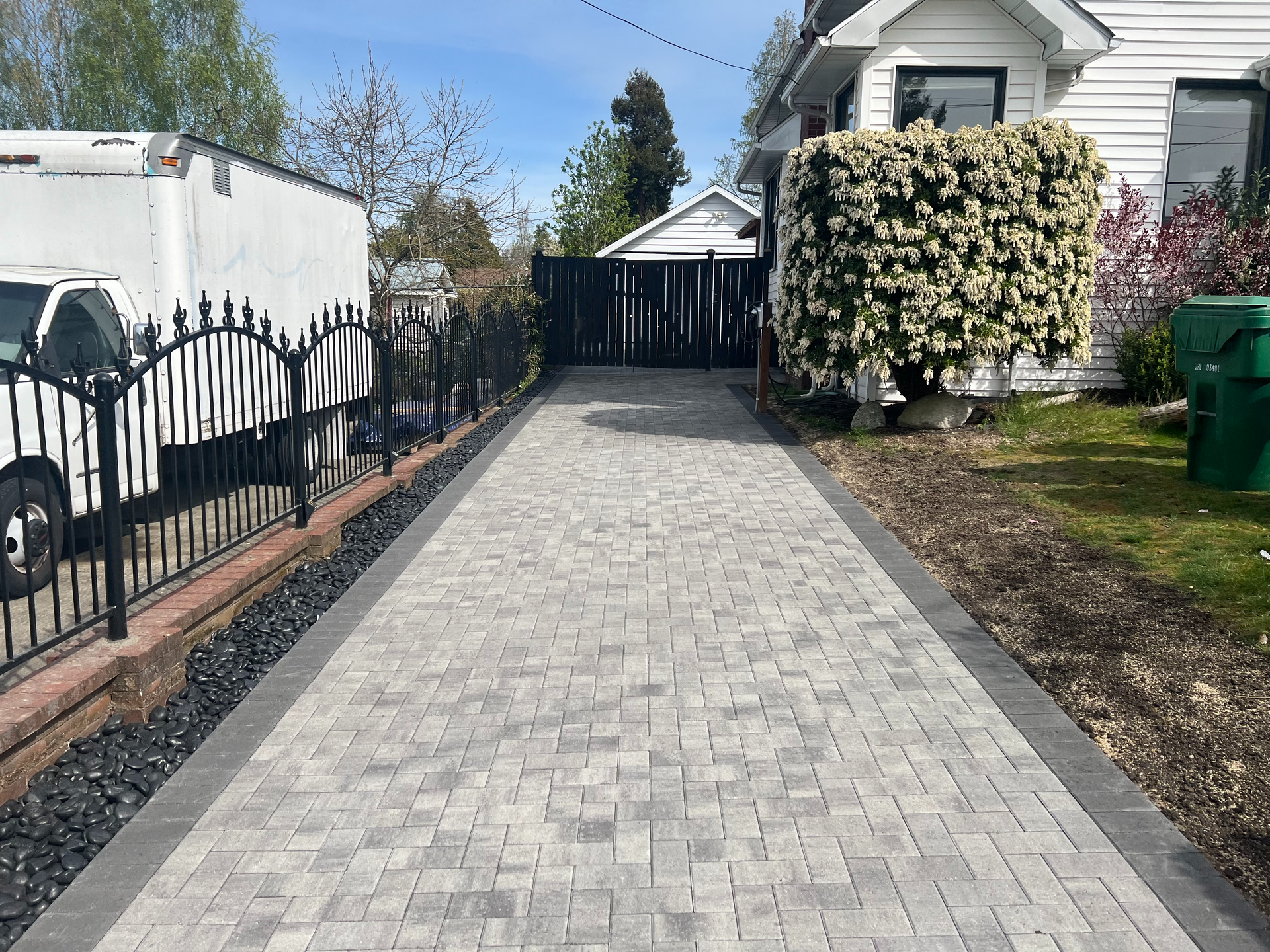 A brick driveway leading to a house with a white truck parked in front of it.