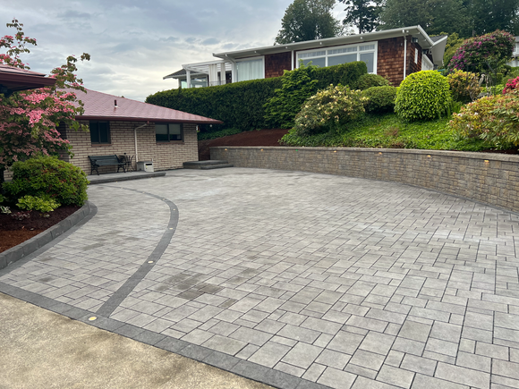 A brick driveway leading to a house on a hill.
