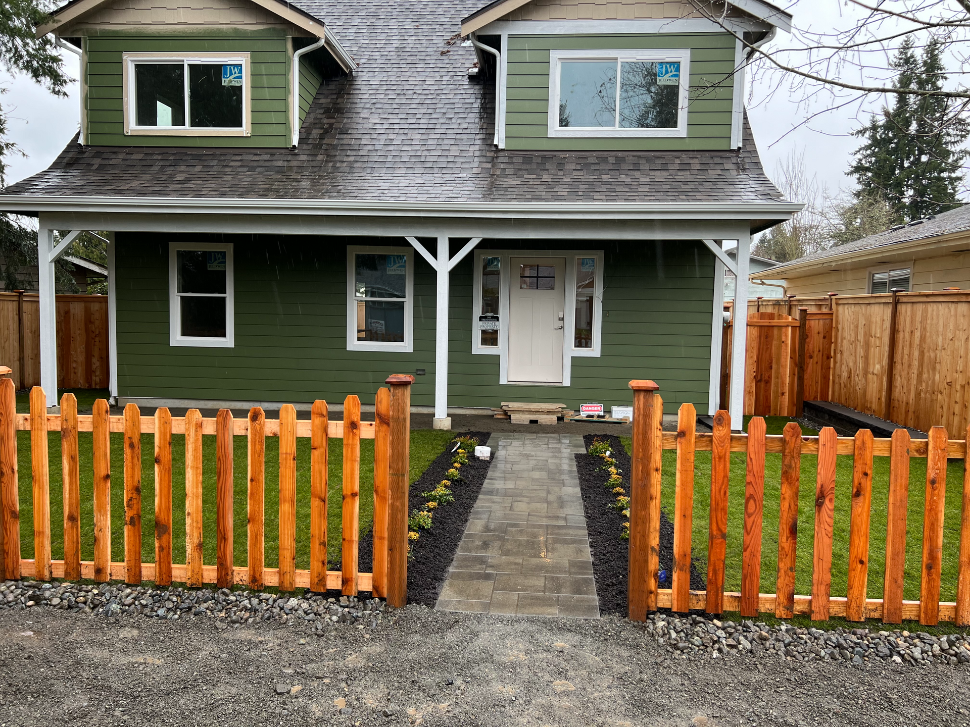 A green house with a wooden fence in front of it.