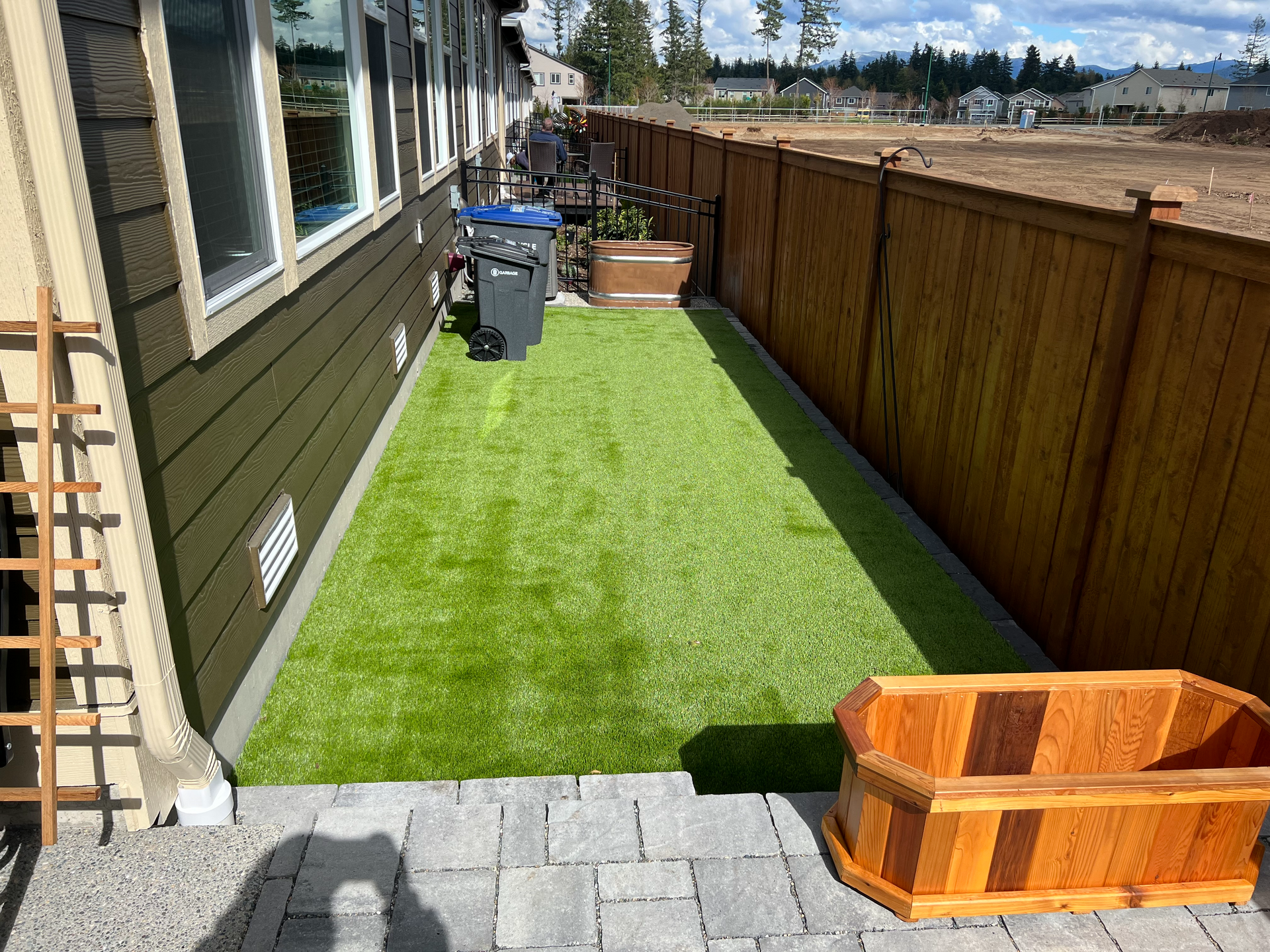 A backyard with a wooden fence and a wooden planter.