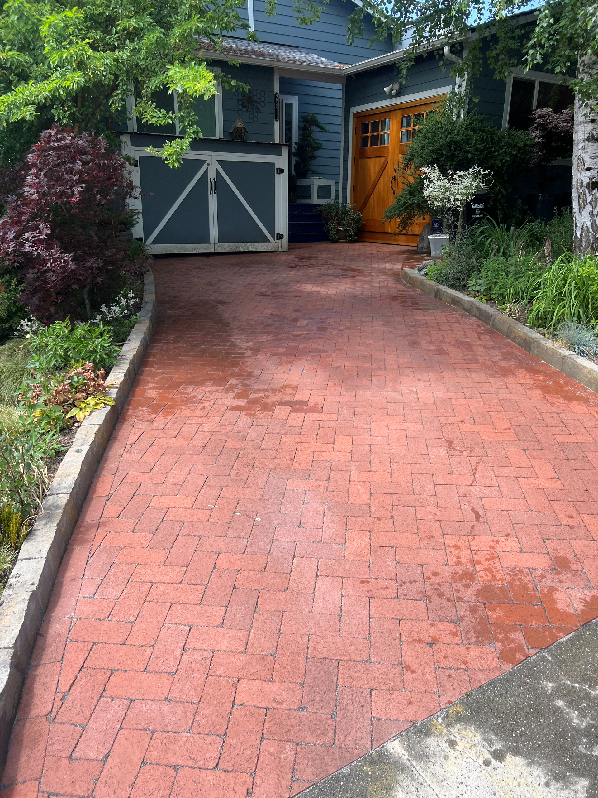 A brick driveway leading to a blue house with a yellow garage door.