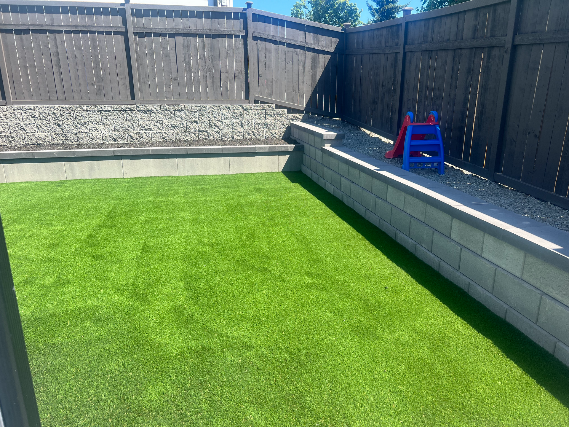 A backyard with a fence and a lush green lawn.