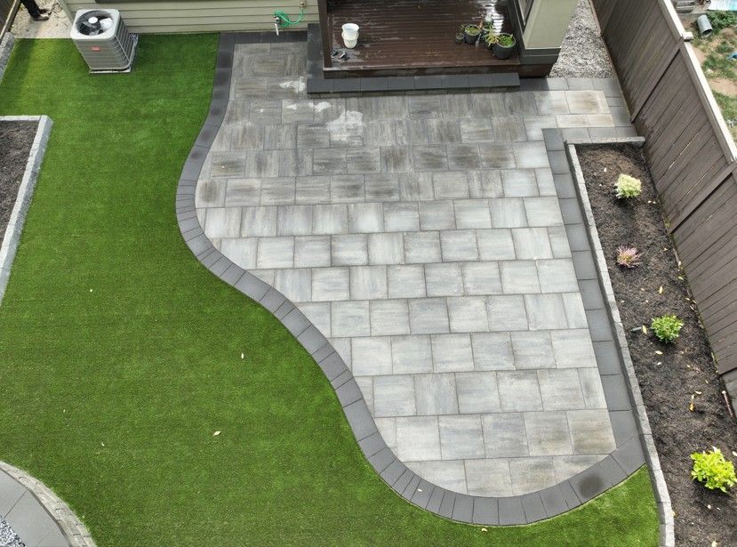 Overhead view of a backyard with a stone patio, artificial lawn, and a small deck.