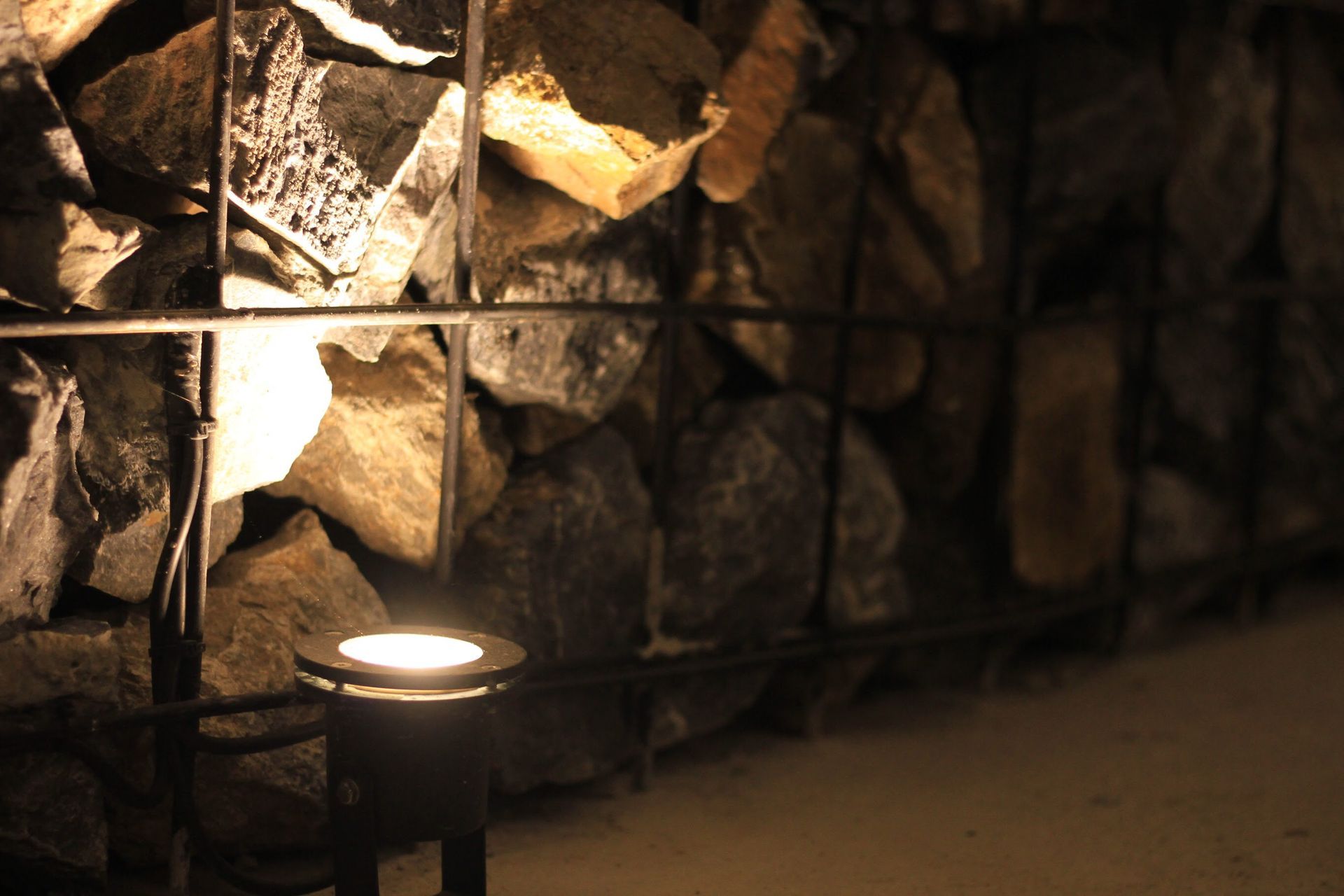 A low spotlight illuminates a stone wall at night.