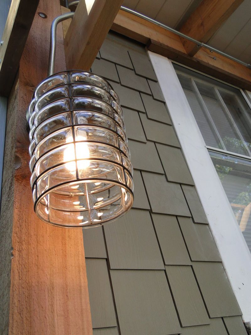 A light is hanging from a wooden post on the side of a house with sage green fiber cement siding and Arctic White trim.