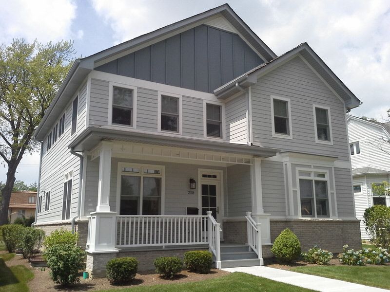 A gray and white house with a large porch