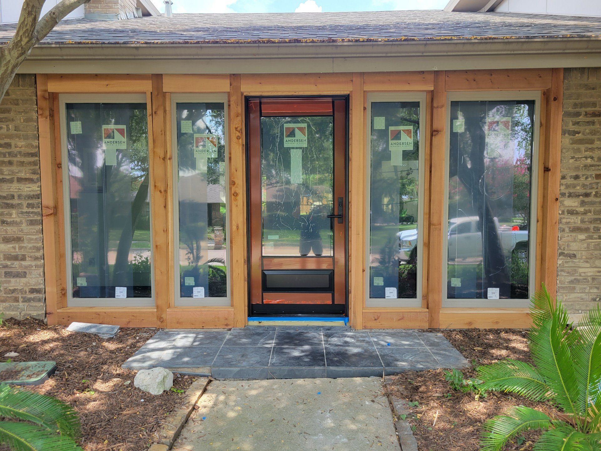 Preview Construction installing an Andersen Architectural front door with Andersen 100 Series fixed units in Sandstone Turnkey Finish.