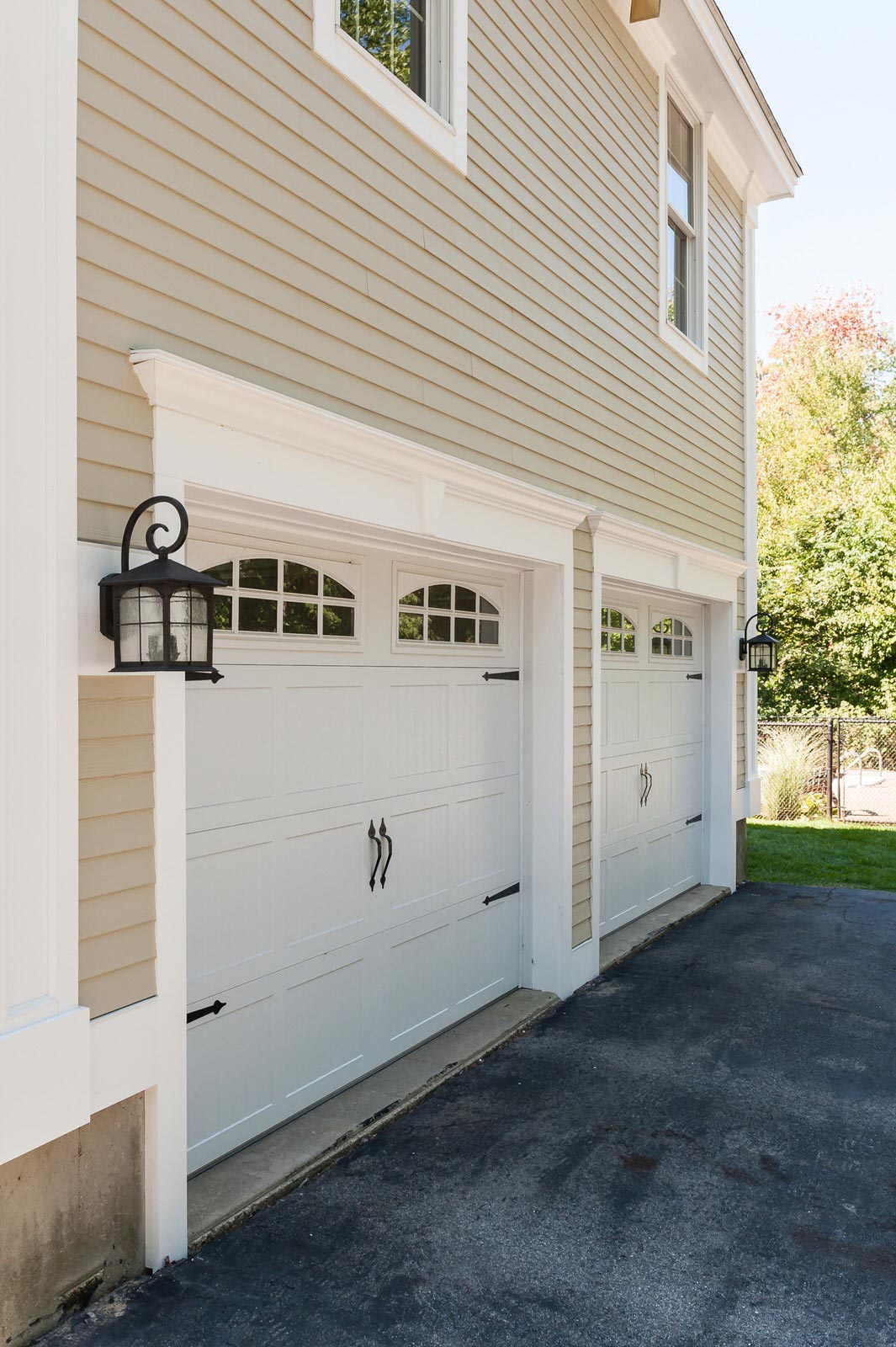 A house with three garage doors and a lantern on the side of it.