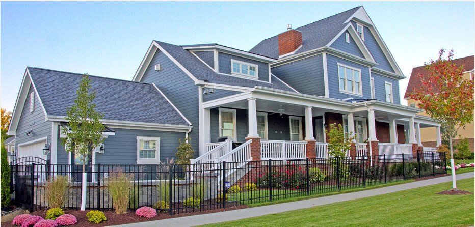 A large blue house with a porch and a black fence