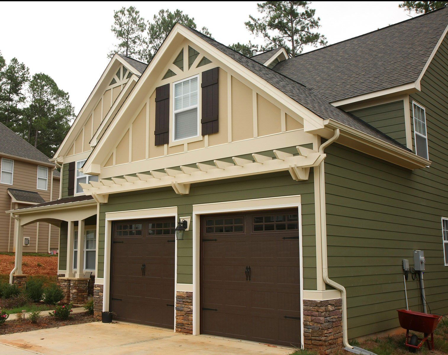 A green and tan house with two brown garage doors