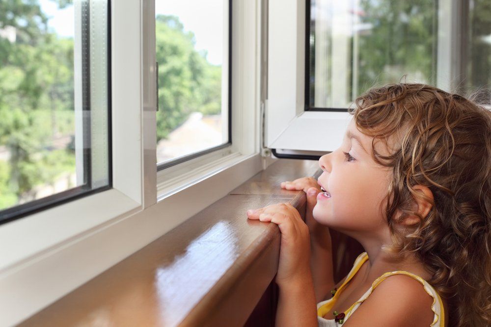 A small girl looking through a house window in Dallas, Texas.