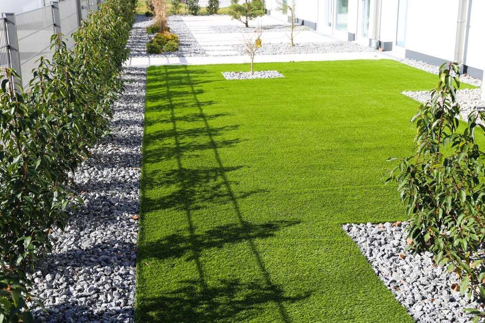 A Lush Green Lawn Surrounded by Bushes and Gravel in a Yard — Oaks Quality Turf In Coolangatta, NSW