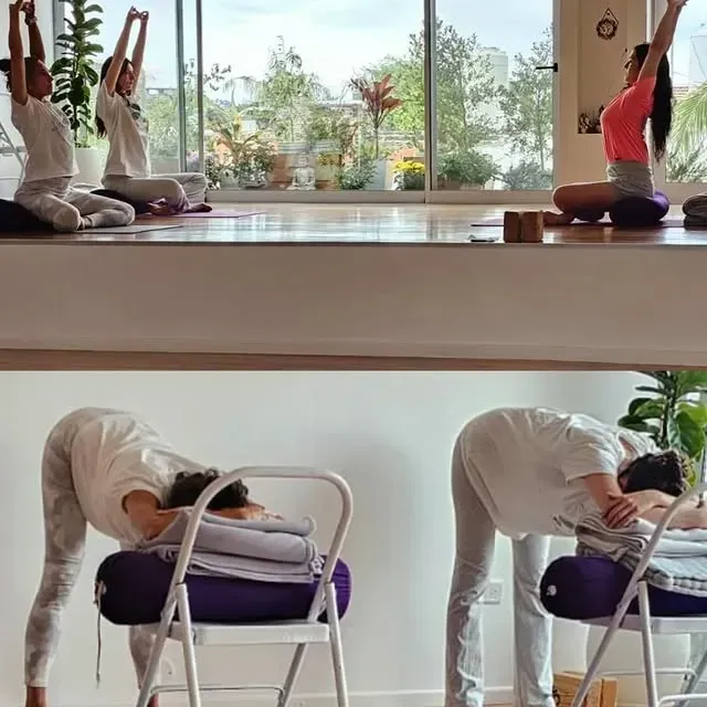 Mujer en pose de yoga, con el brazo levantado, sobre una esterilla morada, sobre un fondo blanco.