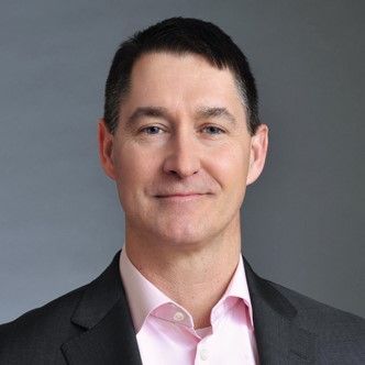 Dave DuRoss Profile Picture - a man in a suit and pink shirt is smiling for the camera .