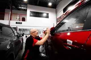 Un homme travaille sur une voiture rouge dans un garage.
