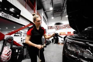 Une femme travaille sur une voiture dans un garage.