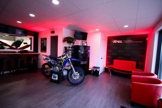 Une moto est garée dans un local aux feux rouges.