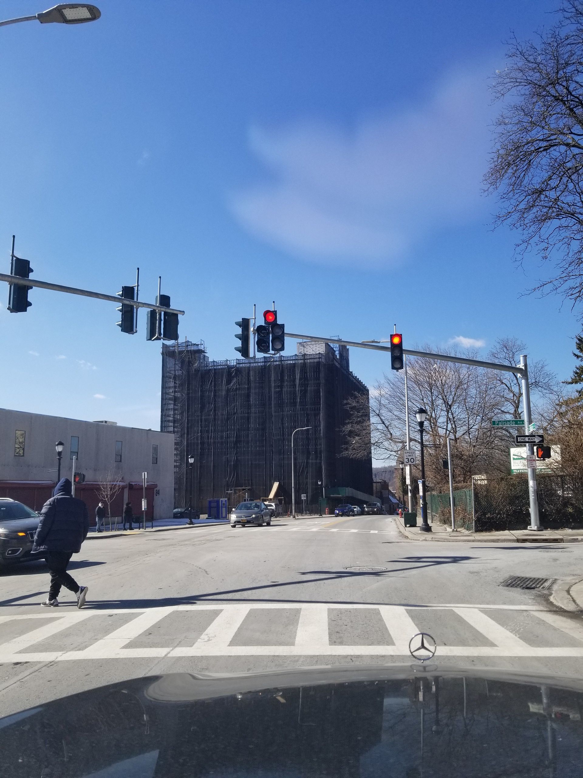 Scaffolding against a concrete building with wooden platforms, likely for construction or renovation. Yellow objects are attached to the structure.