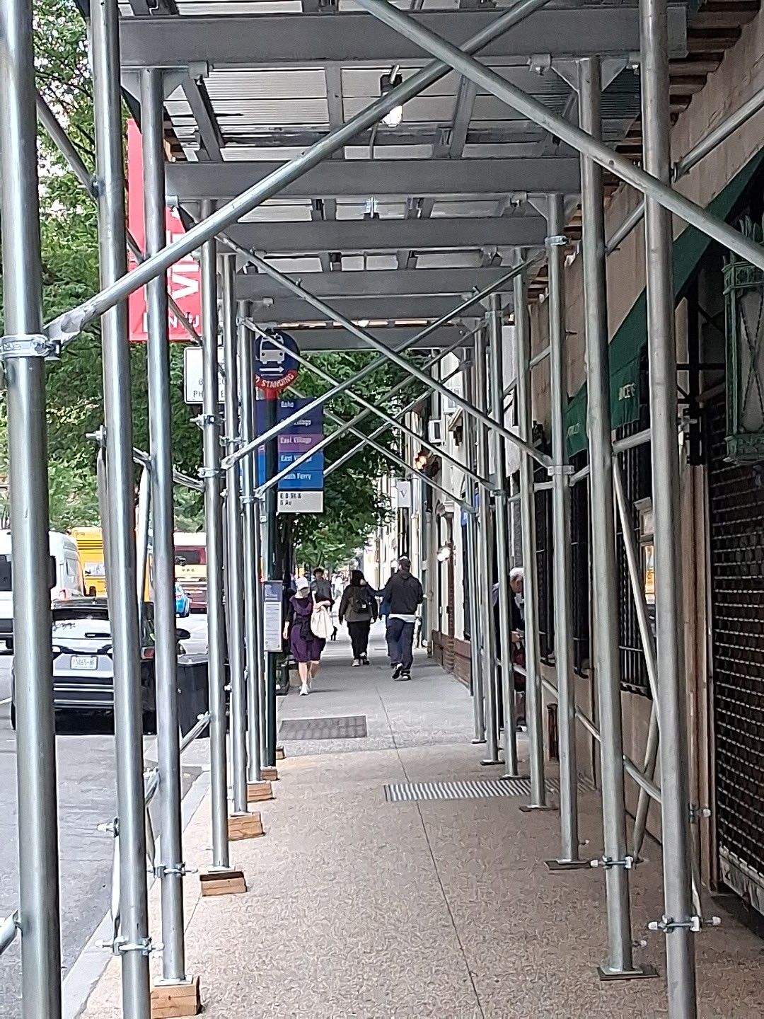 Construction site with a crane, scaffolding, and a brick building under construction against a cloudy sky.