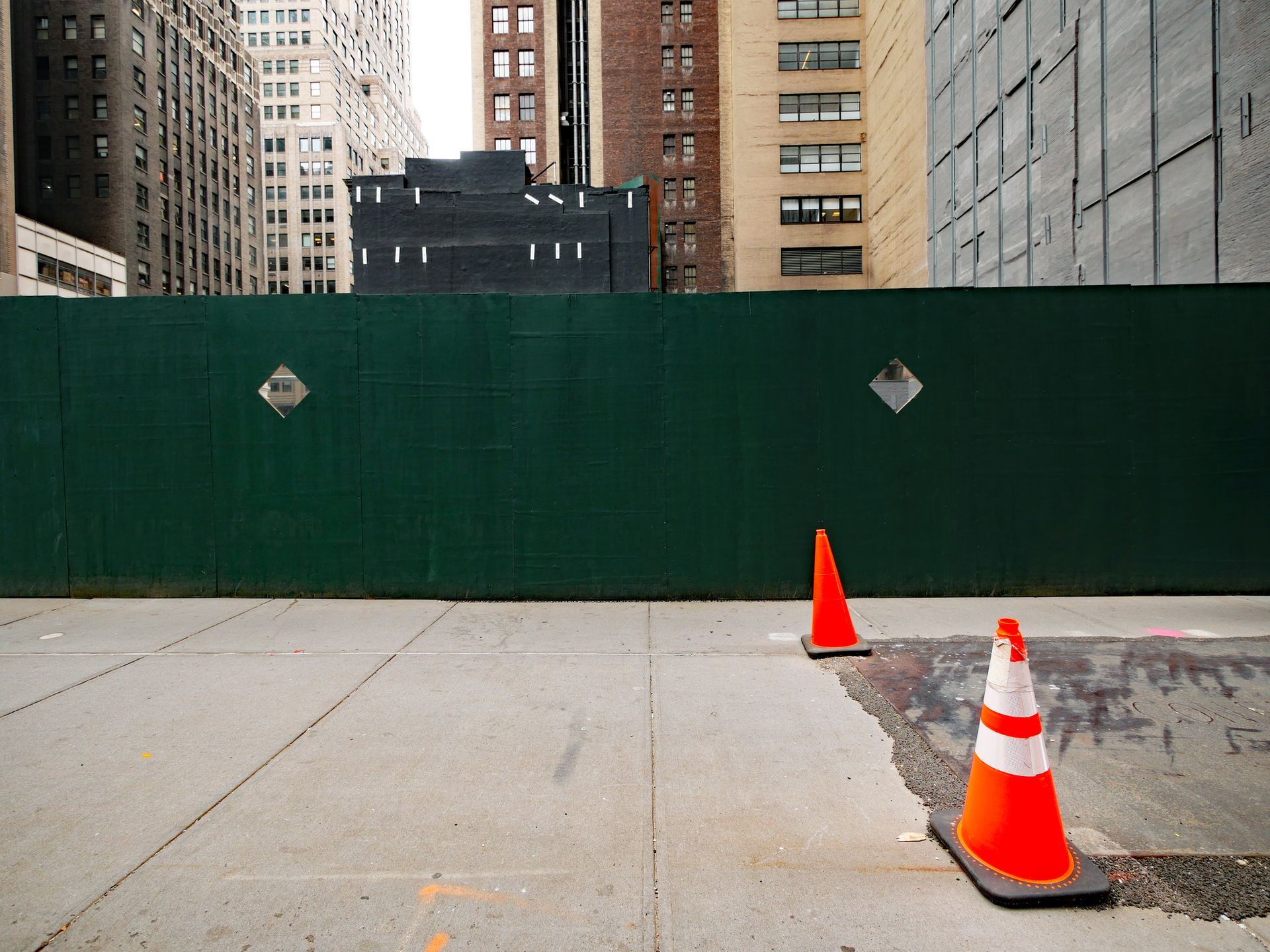 Construction workers wearing safety vests and harnesses on scaffolding against a blue sky with clouds.