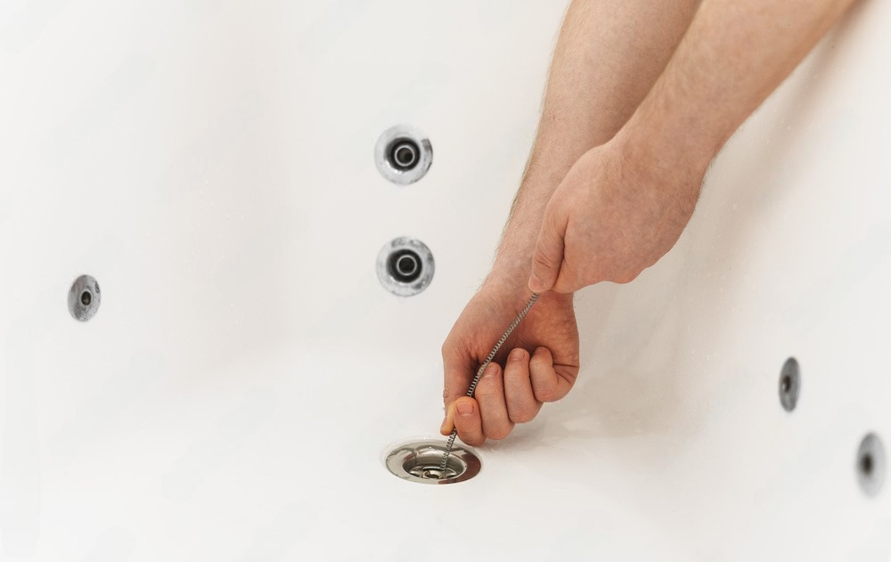 a person is using a tool to remove a drain from a bathtub