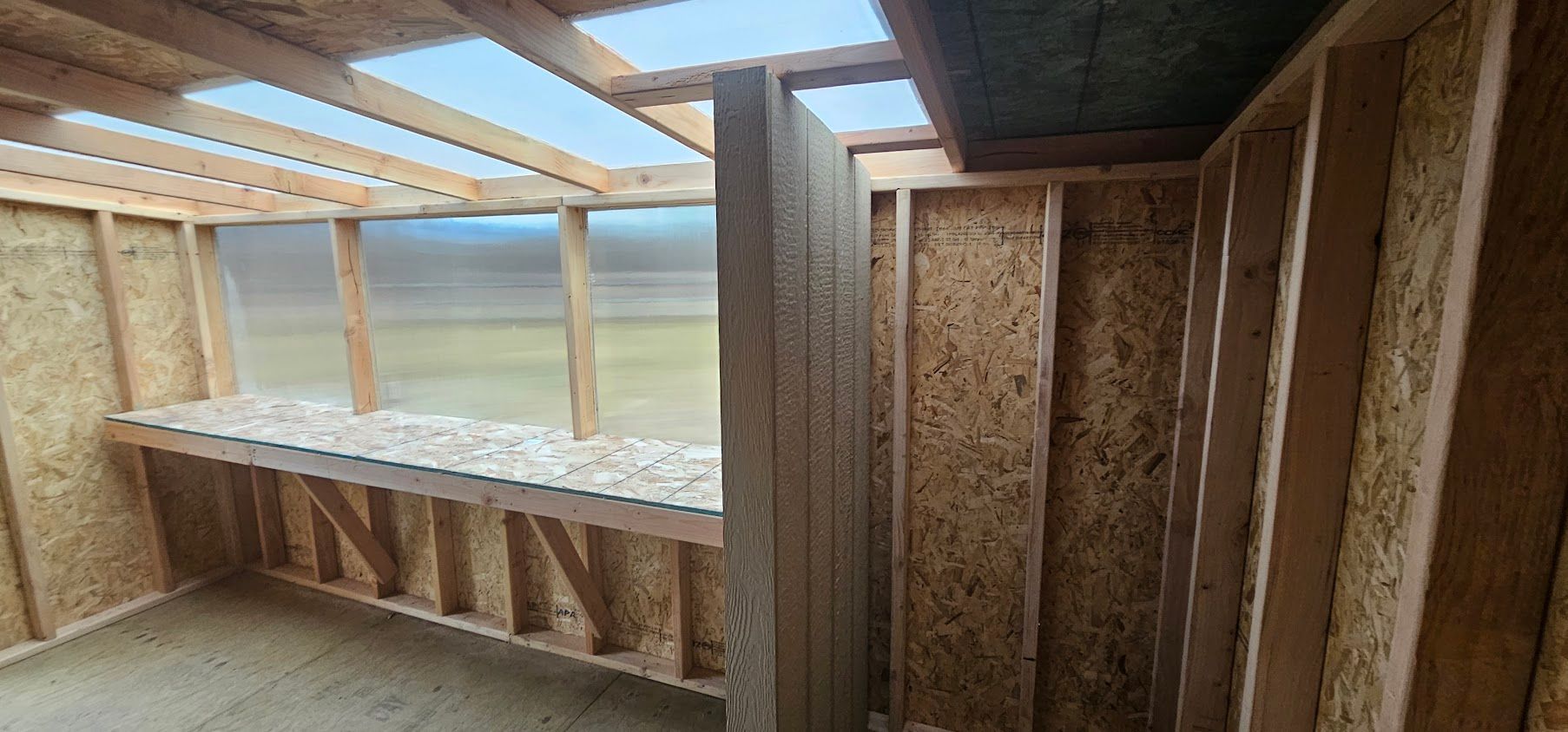 A wooden room with a shelf and a window.