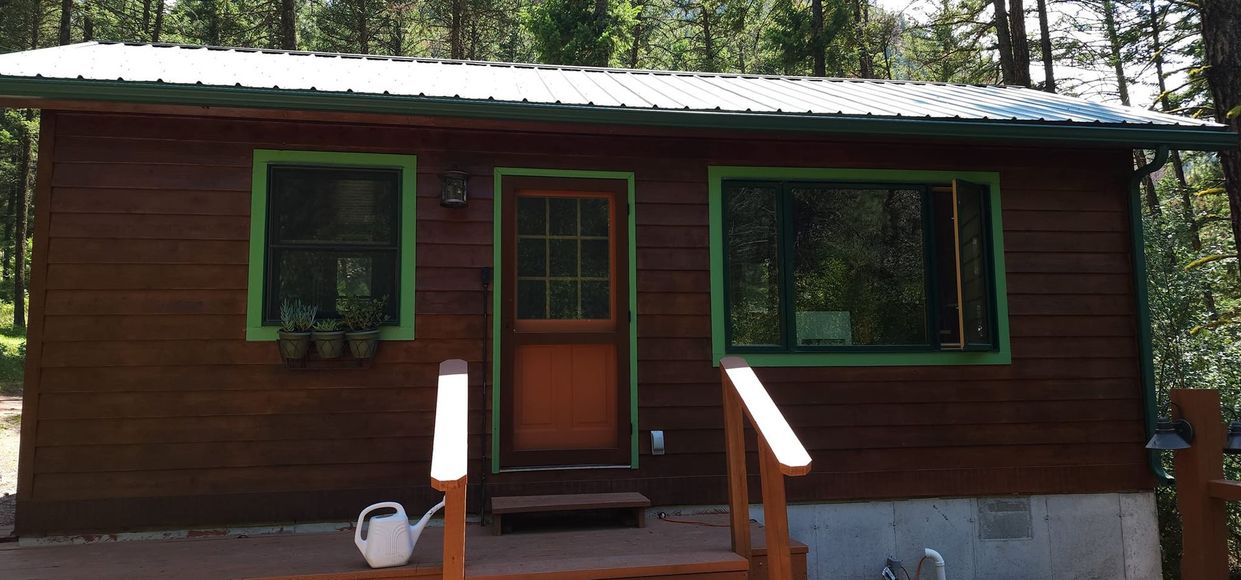 A small wooden house with a watering can on the porch.