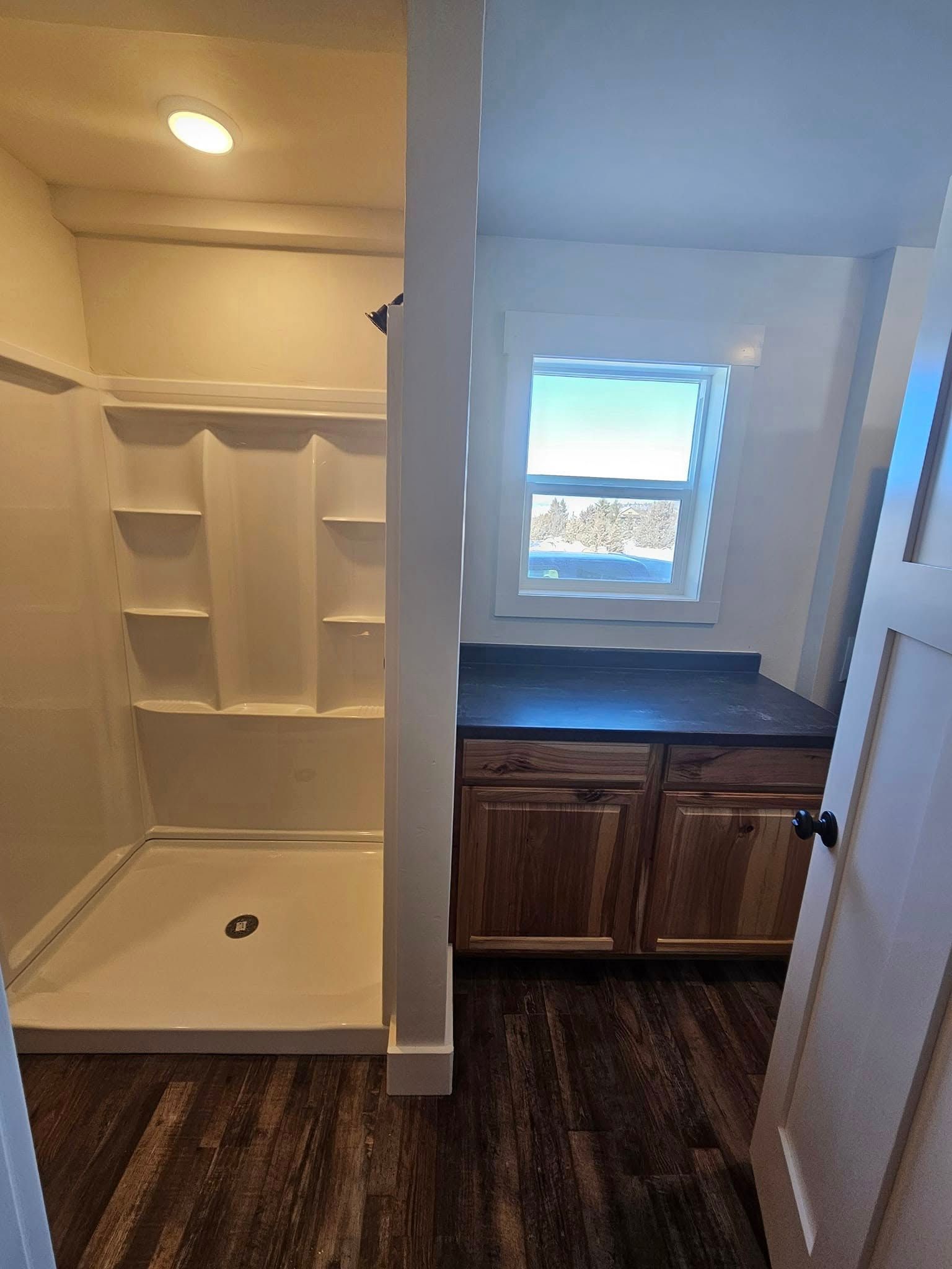 A bathroom with a walk in shower and a window.
