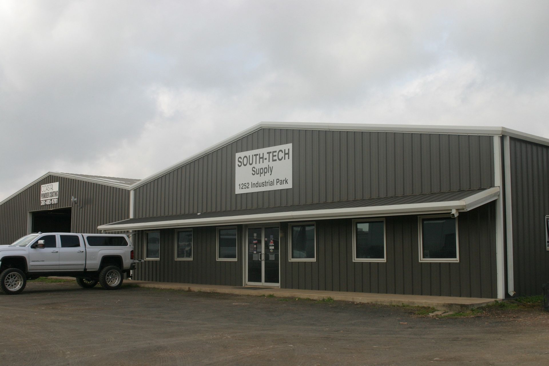 A grey, metal-sided commercial building with the sign 
