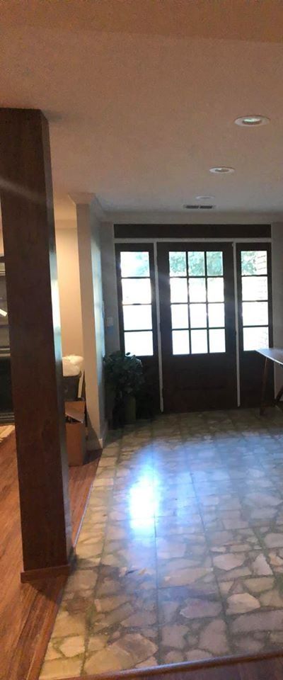 A tiled entryway floor leads to a dark wood front door with glass window panes, framed by side windows.