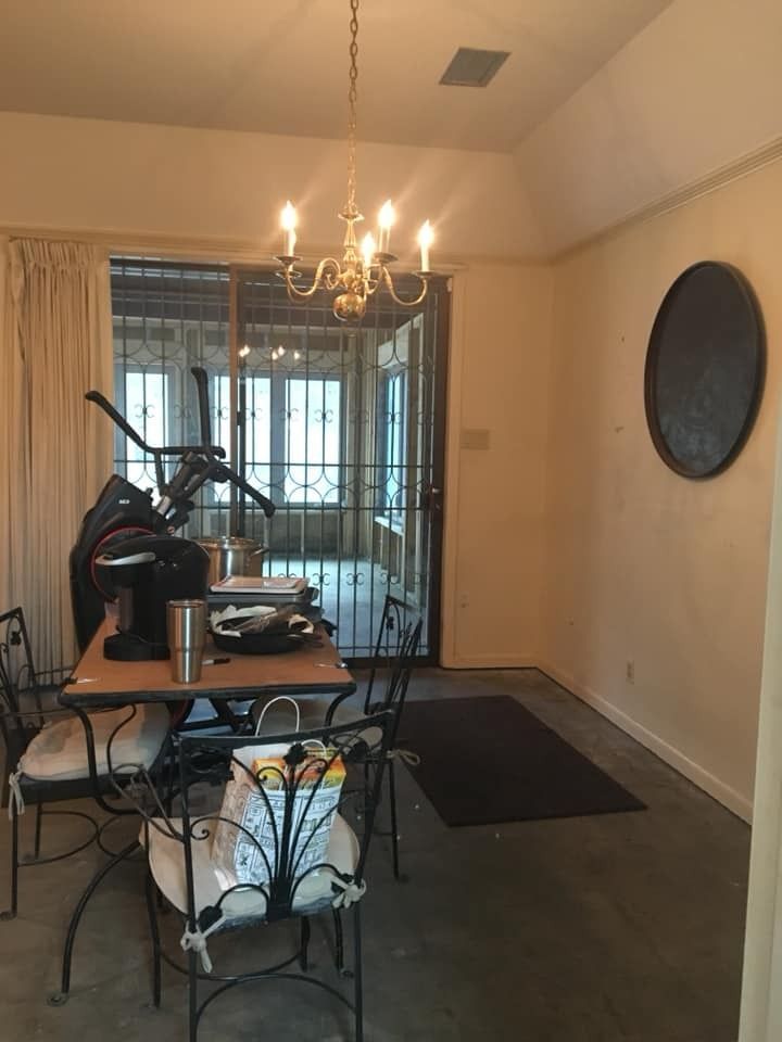 A dining room with a table, chairs, an elliptical machine, a sliding glass door with a security gate, and a wall mirror.