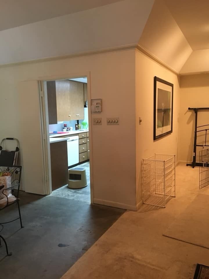 A doorway leading to a kitchen with light wood cabinets and a dishwasher, adjacent to a hallway with a wall-mounted print.