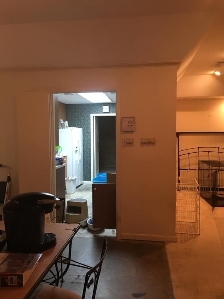 A view through a doorway into a room with a white refrigerator, a dark accent wall, and a tiled floor.