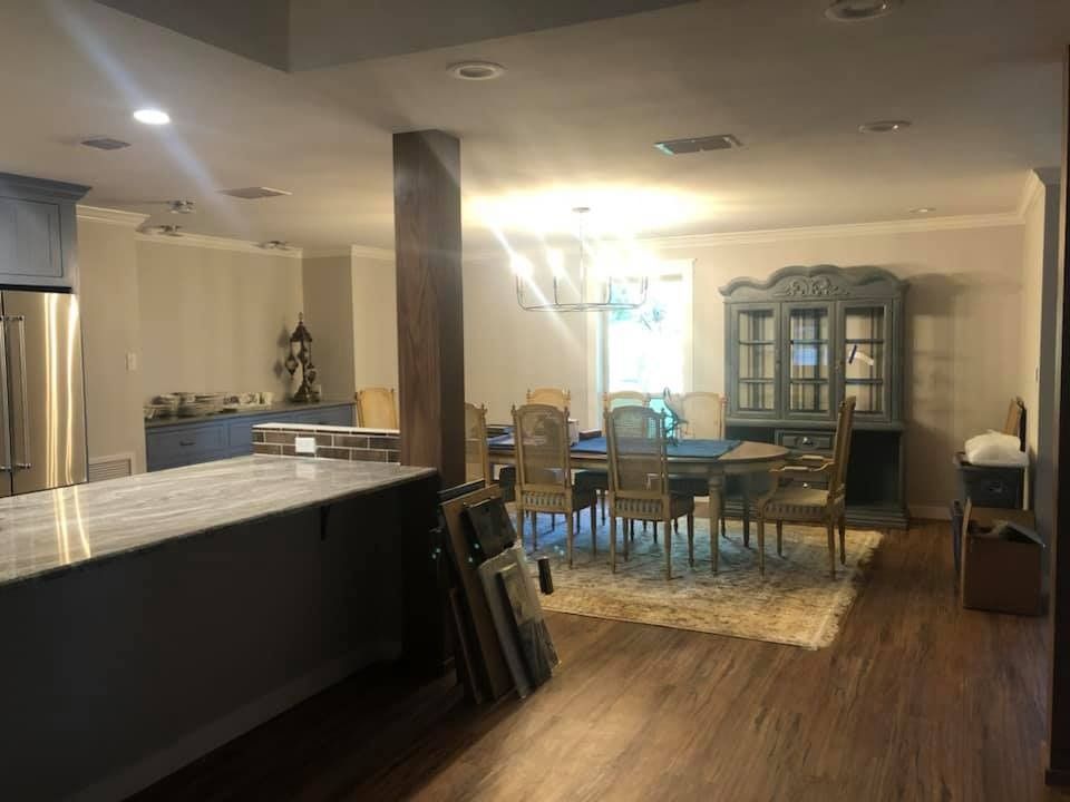 An open-concept kitchen with a large island in the foreground and a dining set on a rug in the background.