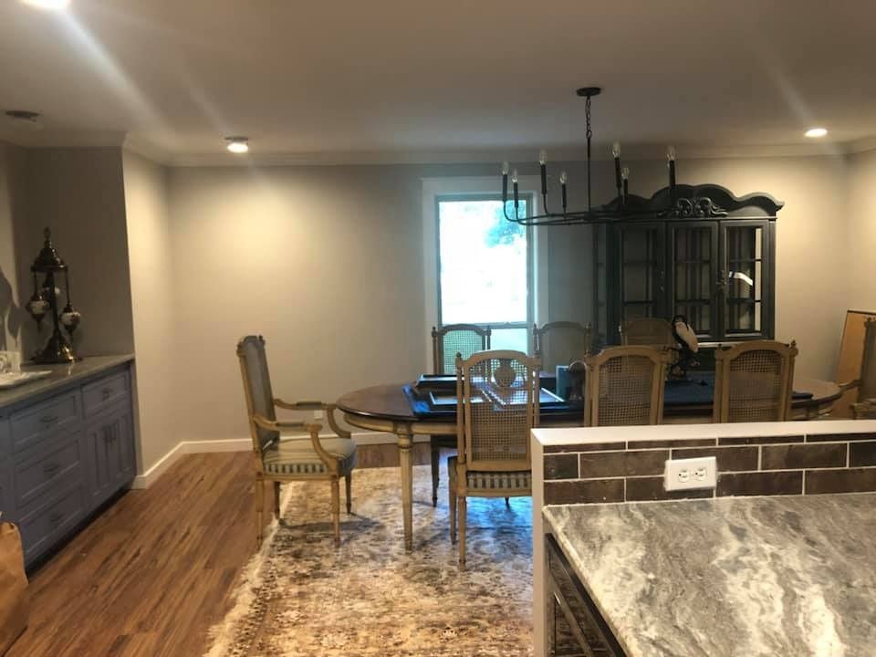 A dining room with a table, chairs, a hutch, a rug, and a kitchen island with a tiled backsplash in the foreground.
