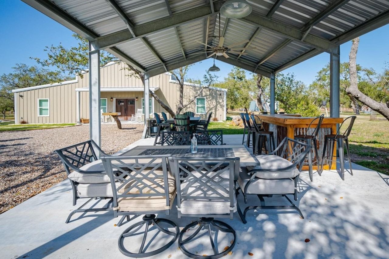 Outdoor patio area with a covered seating arrangement, featuring a dining table, chairs, and a bar counter.