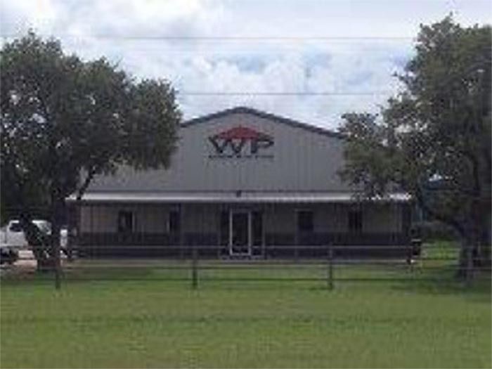 A single-story metal building with a white exterior, a gable roof, and the 