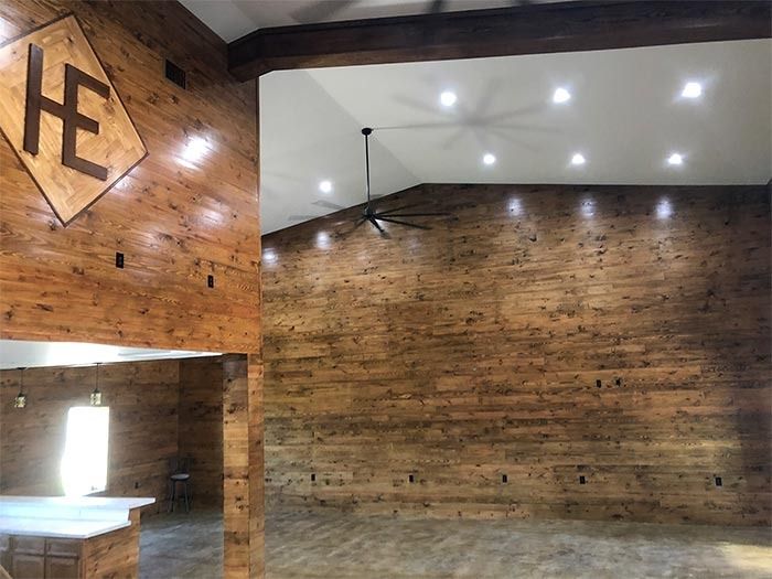 A large, rustic indoor space featuring high, vaulted ceilings, wooden paneled walls, and a prominent 