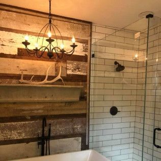 A rustic bathroom featuring a chandelier, a wooden wall with an antler decoration, and a glass-enclosed shower.