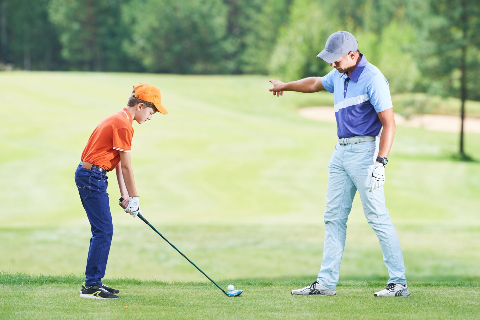 A man is helping a woman putt a golf ball on a golf course.