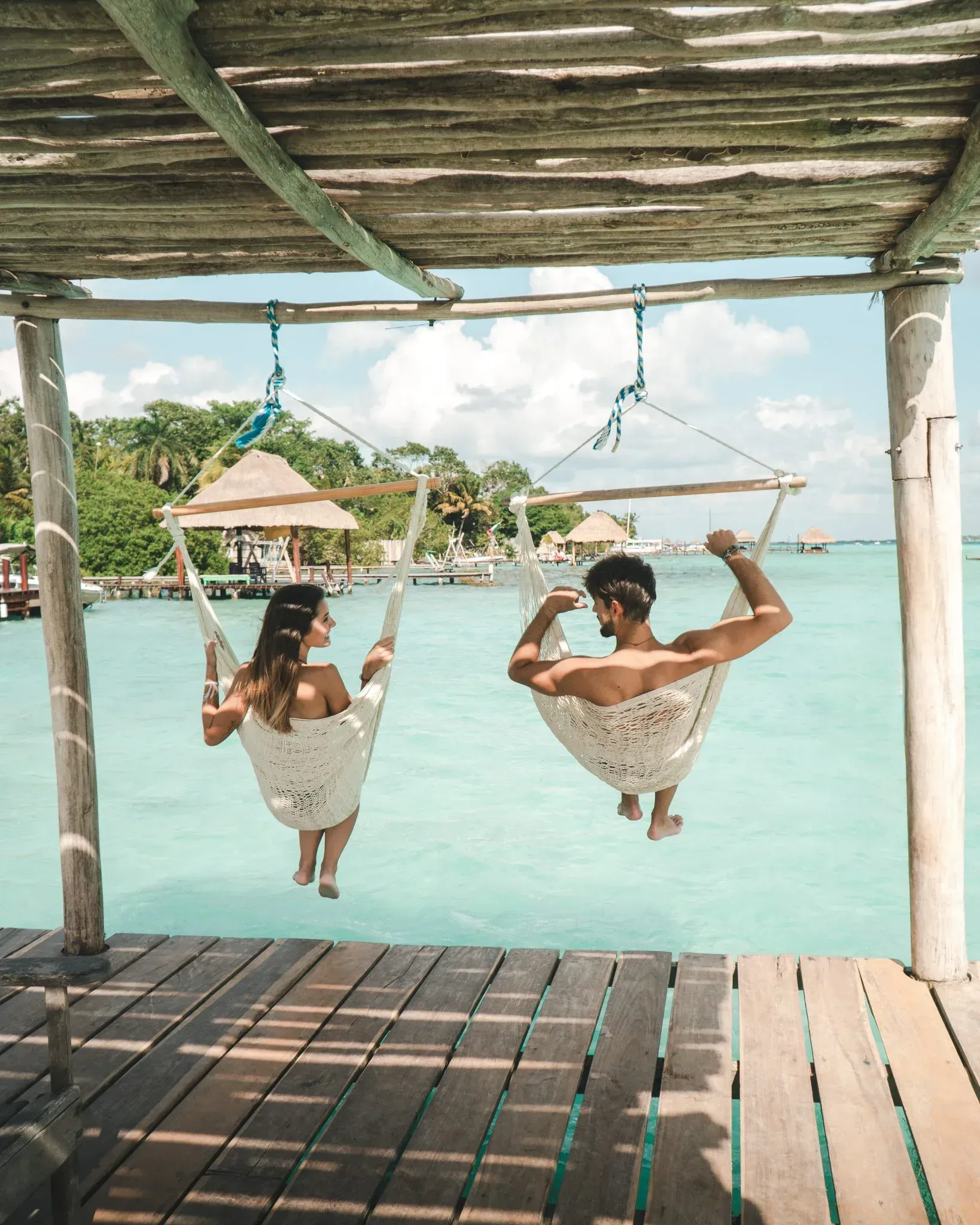 A couple sits down in a hammock.