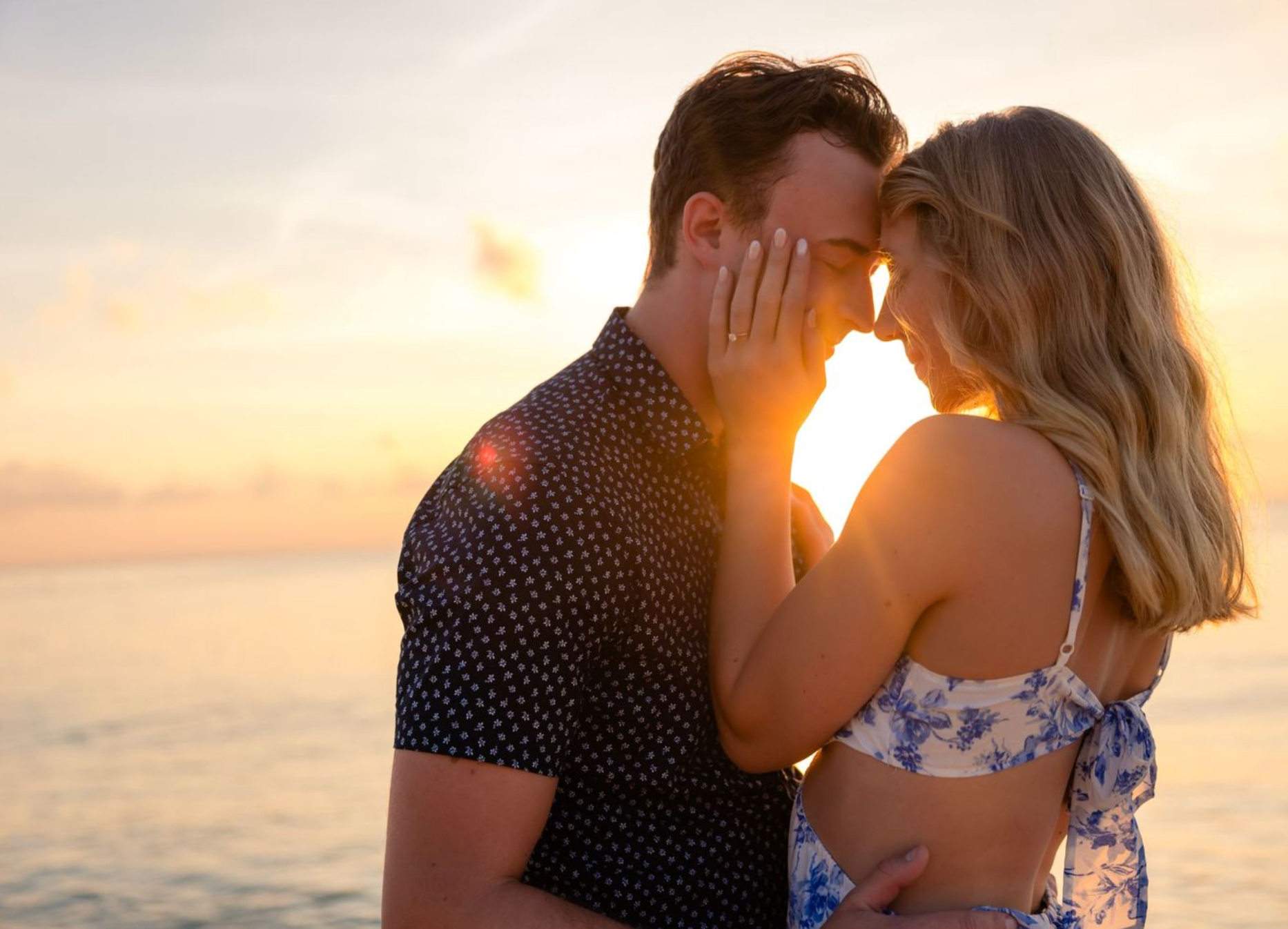 Una pareja romántica con el atardecer atrás.