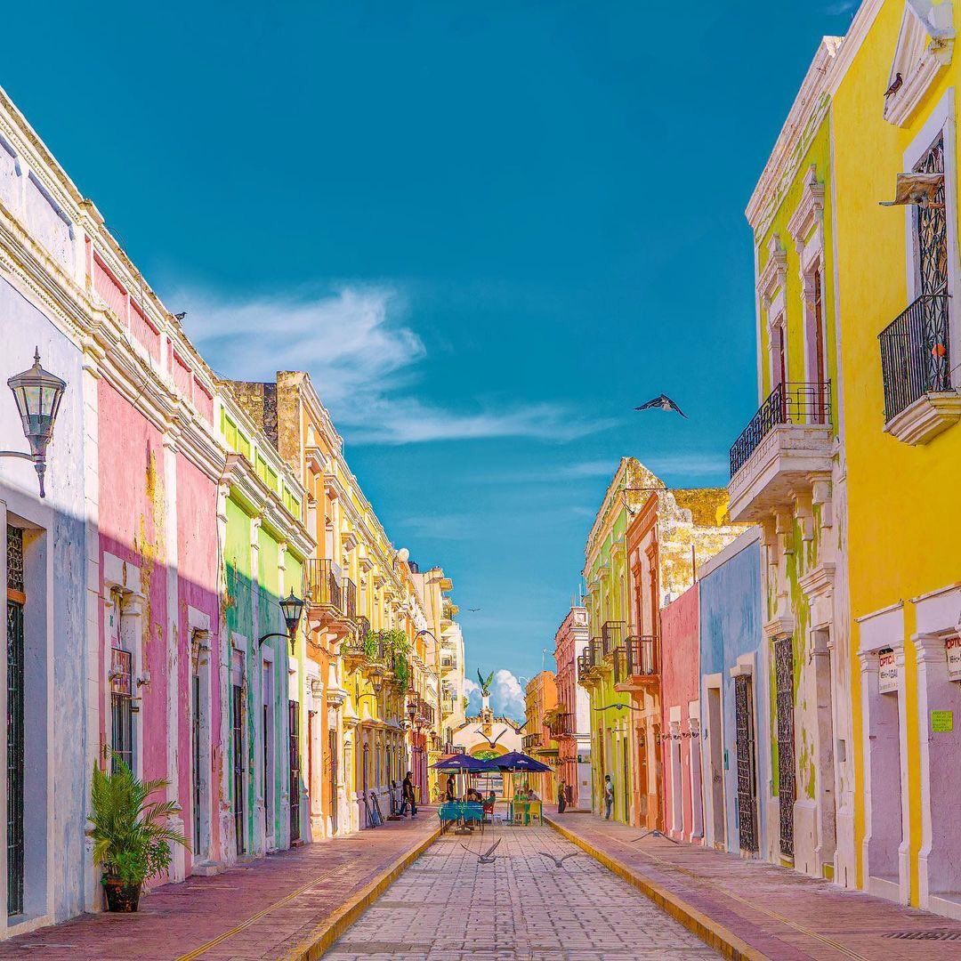 A narrow street lined with colorful buildings on a sunny day.