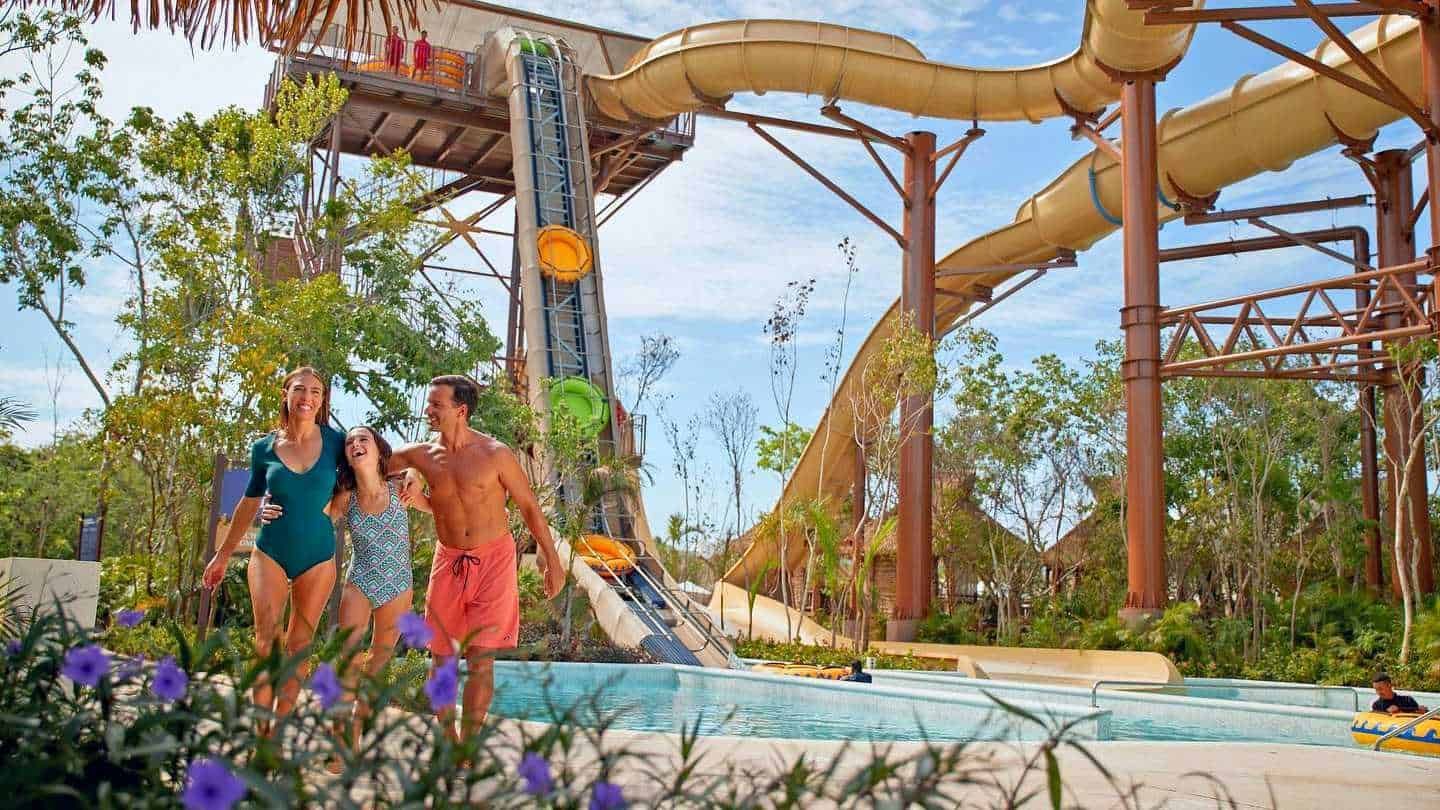 A group of people are standing in front of a water slide at a water park in Cancun