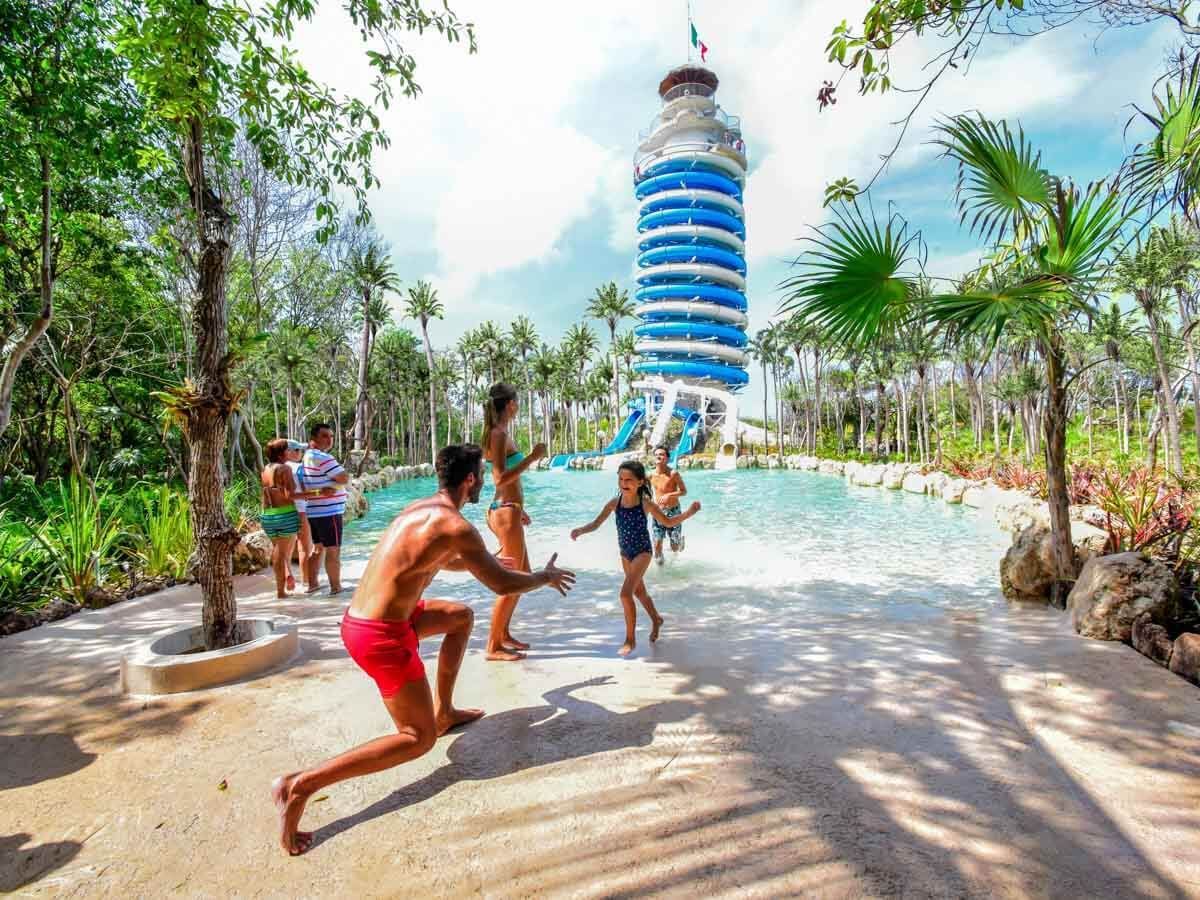 A group of people are playing in a pool with a lighthouse in the background.