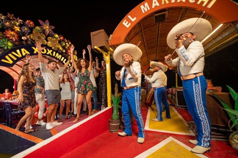 A group of people are standing in front of a mariachi band.