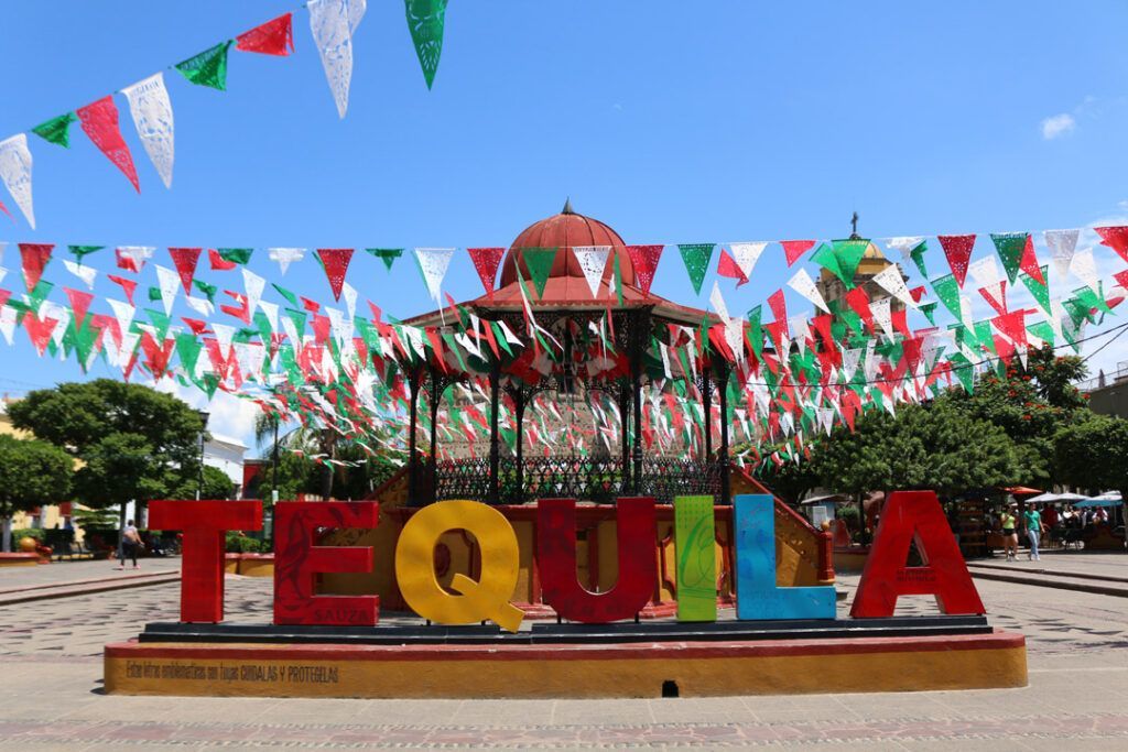 A sign that says tequila is surrounded by mexican flags.