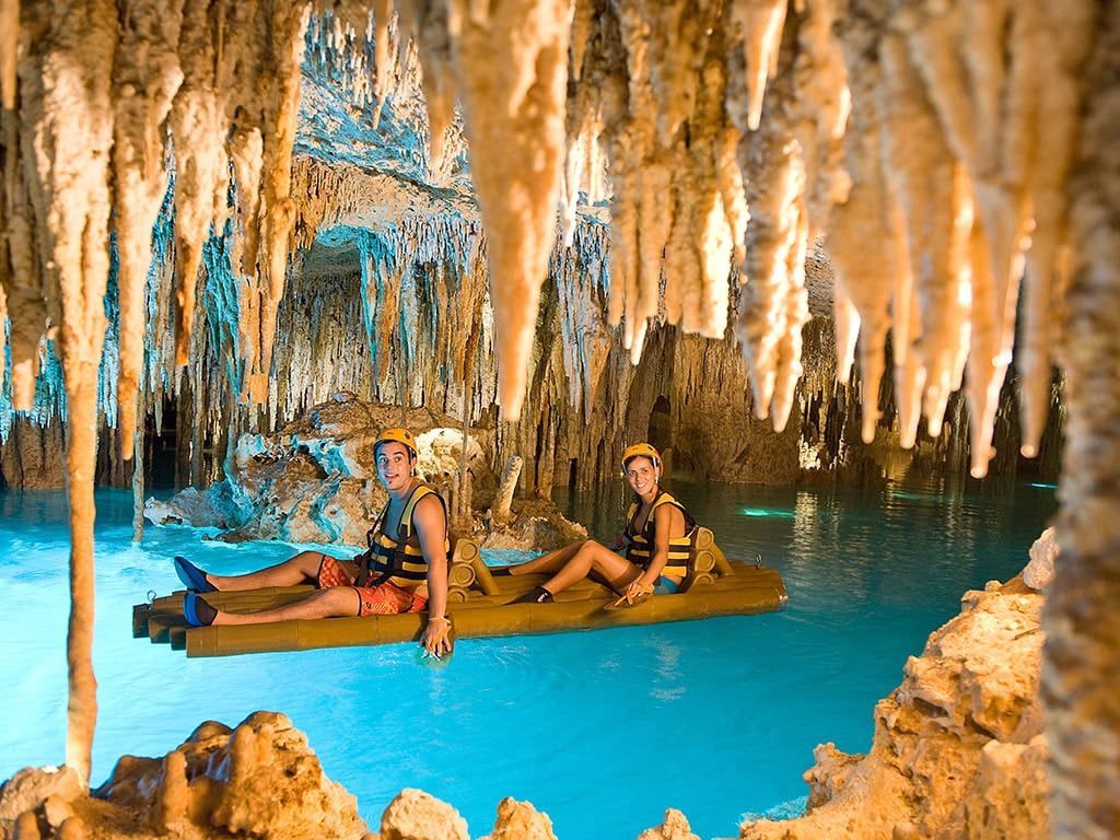A man and a woman are floating on a raft in a cenote.